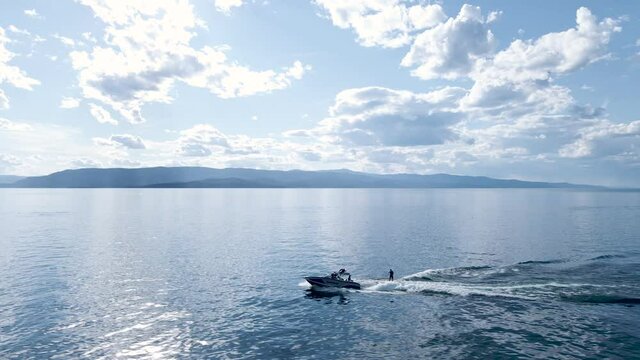 Wake Surfers Boating on Breathtaking Scenic View of Calm Lake with Sky Reflection - Aerial Drone