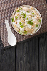 Ginger chicken Jook Rice Porridge close-up in a bowl. Vertical top view
