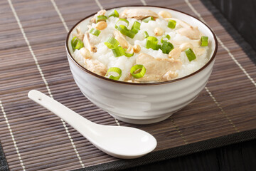 Slow cooked ginger rice porridge with chicken, peanuts and green onions close-up in a bowl. horizontal