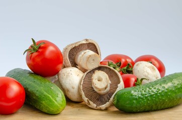 Tomatoes cucumbers mushrooms. Fresh summer vegetables and white mushrooms. Red and green vegetables background.