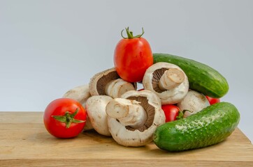 Tomatoes cucumbers mushrooms. Fresh summer vegetables and white mushrooms. Red and green vegetables background.