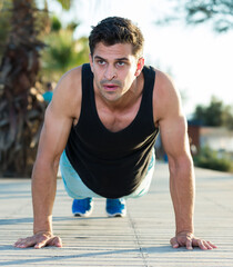 Fototapeta premium Portrait of athletic man training on beach doing press up exercises