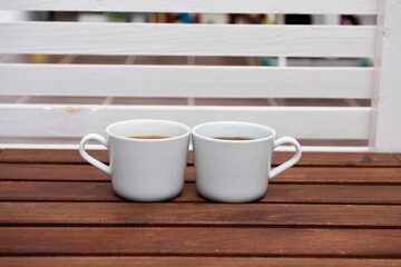 A pair of white Cups of Turkish coffee on striped wooden table. Side View