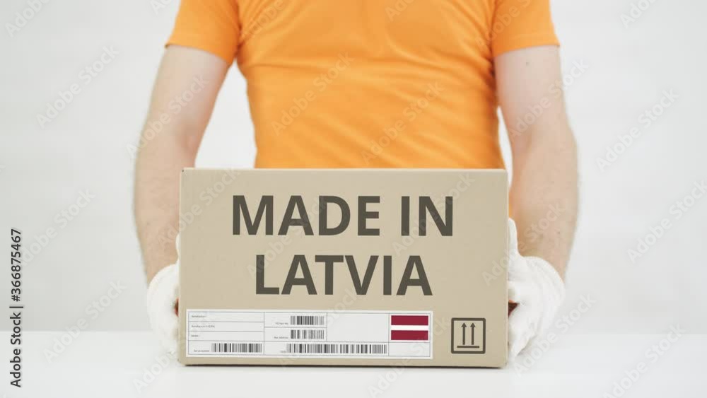 Poster man puts cardboard box with made in latvia text on the table
