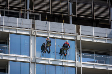 workers clean glass in a high-rise building at a height