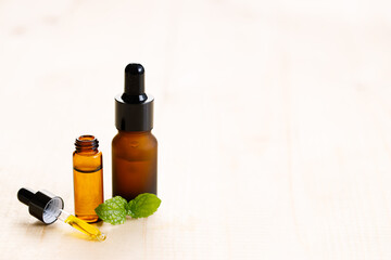 Peppermint essential oil with fresh mint leaves on wooden background