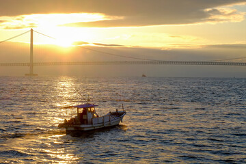 Fototapeta na wymiar 明石海峡大橋と朝日に照らされた海を行く船