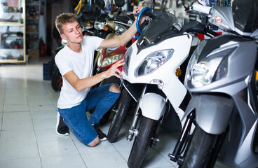 Fototapeta na wymiar Portrait of happy italian male motorcyclist looking on the bike in the store