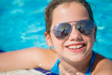 Teenager girl with sunglasses looking out of the pool