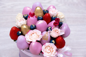 The most beautiful bouquet of fresh strawberries in white, pink and gold chocolate on a light background.