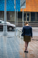 a girl in a blue sweater is waiting in the rain