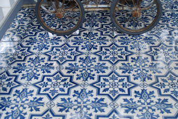 Fototapeta na wymiar 美しい模様の青いタイルの床とアンティークの乳母車の車輪