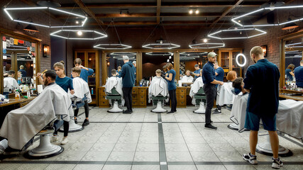 People at barbershop. Professional barbers serving clients in the modern loft style barber shop. General view. Hairdresser services