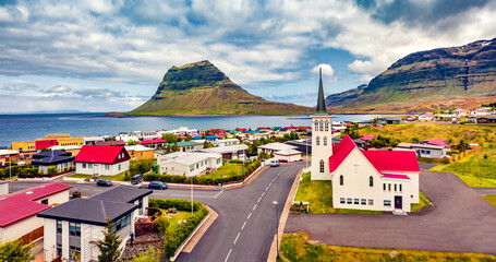 View from flying drone. Splendid morning cityscape of Grundarfjordur town with Kirkjufell Mountain on background. Panoramic summer view of Grundarfjordur Church, Iceland, Europe.