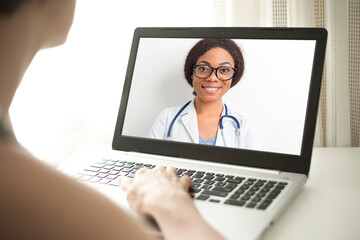 Fototapeta na wymiar The doctor virtually consults the patient on the laptop screen. African American woman online video call provides medical assistance.
