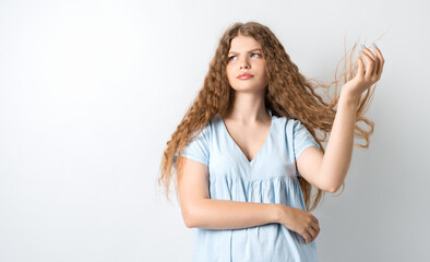 Portrait of attractive european girl, discontentedly tilting head and shaking curly hair. Isolated over white background.