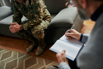 Cropped shot of military man during therapy session with psychologist. Soldier suffering from...