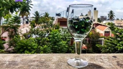 glass of marbles and green background.