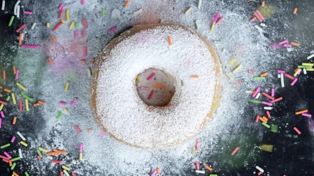 Close up slow motion top angle shot strew colorful chocolate rice with donut