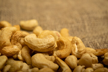 A pile of cashew nuts on burlap with a rough texture surface texture. Close up.