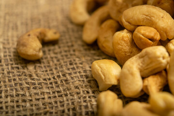 A pile of cashew nuts on burlap with a rough texture surface texture. Close up.
