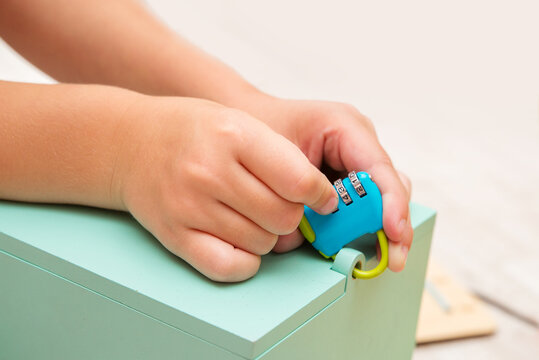 
Close-up of children's hands holding a lock with a code to guess the code on the lock and open the box