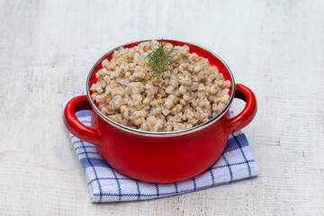 Red pan with boiled wheat porridge . Closeup