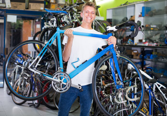 Fototapeta na wymiar .Smiling young buyer holding bicycle in the hand at the store