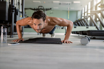 Fototapeta na wymiar Muscular build man doing push-ups in a gym.