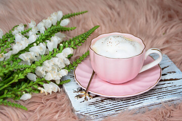 Morning coffee. Cup of coffee, latte with flowers on pink fur background. Coffee concept