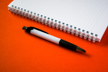 Cut out notepad with pen on orange background