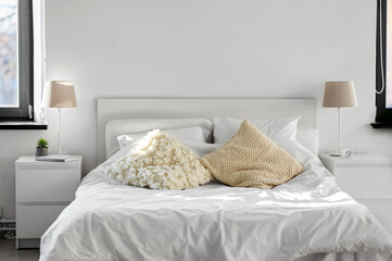 coziness, interior and living concept - cozy bedroom with cushions and bed linen at home