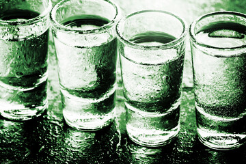 Glass vodka shots. Many alcohol drinks in a row texture. Weekend party background. Green wet bar...