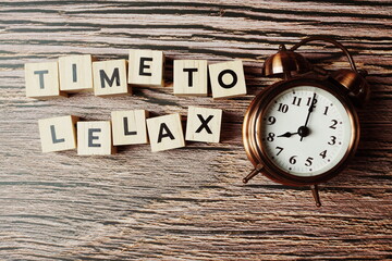 Time To Relax alphabet letter with alarm clock on wooden background
