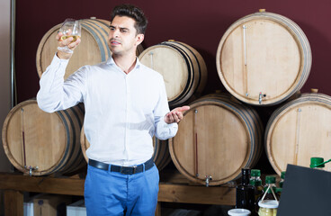Smiling man tasting glass of hard liquor in alcohol section in store