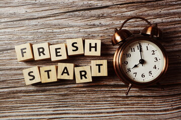 Fresh Start alphabet letter with alarm clock on wooden background;