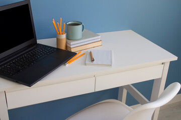 Home office of creative entrepreneur or student with black laptop on white table. Distance online education, work from home concept.