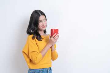 Naklejka premium Young asian woman in yellow sweater holding a cup of coffee