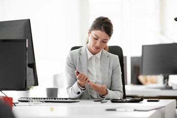 Close up of businesswoman using lancet pen in office. Young woman checking blood sugar level	