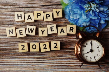 Happy New Year 2022 with alarm clock on wooden background