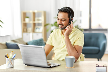 remote job, technology and people concept - happy smiling indian man with headset and laptop computer having conference call at home office