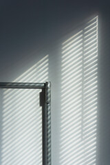 Abstract of morning light and shadow on wall through window blind shutter.  Light through blinds window. Parallel lines of light and reflection provide