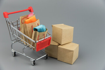 Shopping cart with purchases - packages and boxes on trendy gray background with copy space...