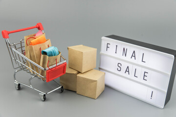 Shopping cart with purchases - packages and boxes on trendy gray background with copy space...