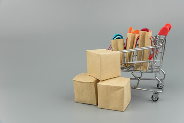 Shopping cart with purchases - packages and boxes on trendy gray background with copy space...