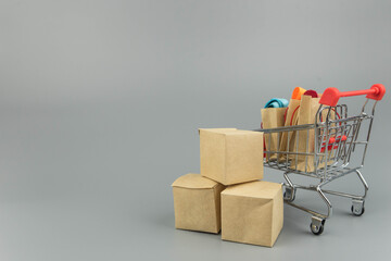 Shopping cart with purchases - packages and boxes on trendy gray background with copy space...
