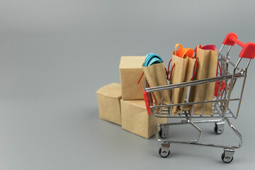 Shopping cart with purchases - packages and boxes on trendy gray background with copy space...