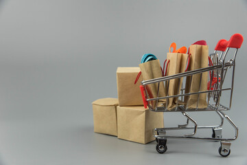 Shopping cart with purchases - packages and boxes on trendy gray background with copy space...