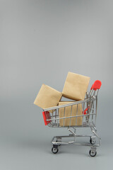 Shopping cart with purchases - packages and boxes on trendy gray background with copy space...
