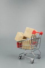 Shopping cart with purchases - packages and boxes on trendy gray background with copy space...
